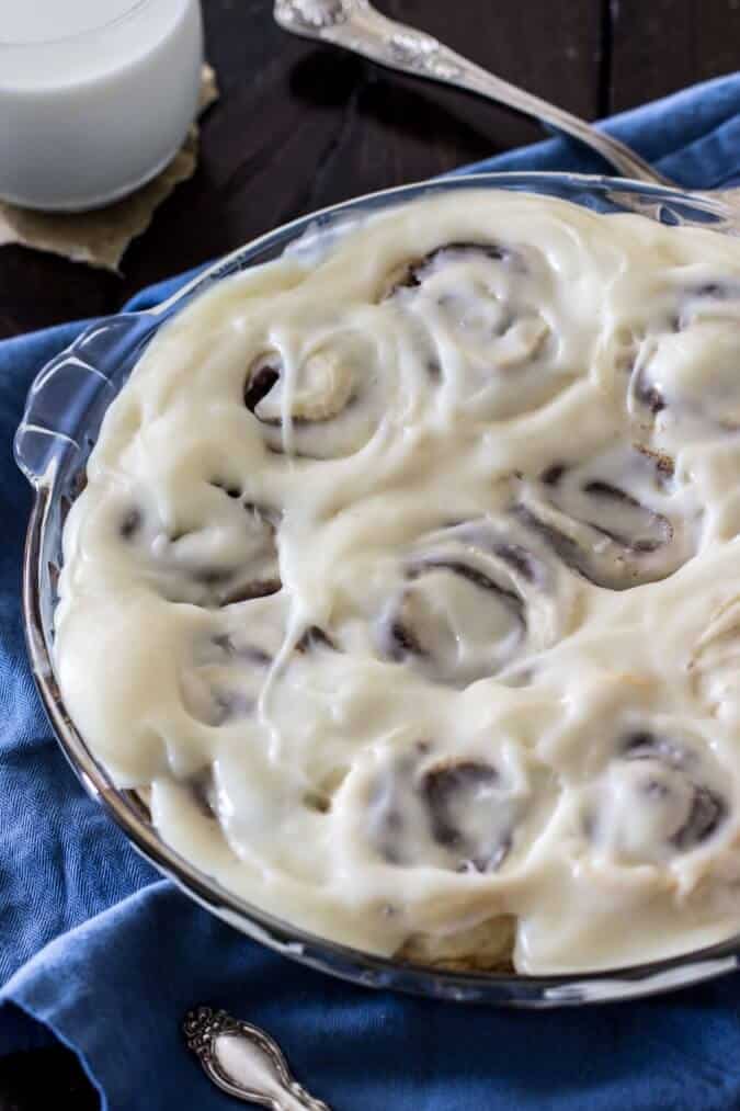 Iced cinnamon rolls in a glass pie dish
