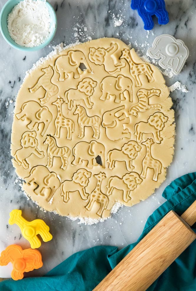 How to make adorable FROSTED ANIMAL COOKIES! Simple and sweet, no chilling required! Rolled out cookie dough on marble with animal shapes cut into dough for animal cookies