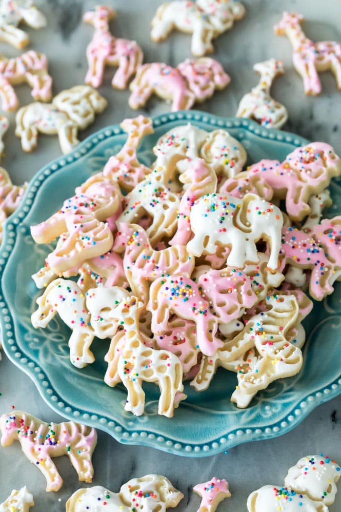 How to make adorable FROSTED ANIMAL COOKIES! Simple and sweet, no chilling required! Pink and white frosted animal cookies on a blue plate