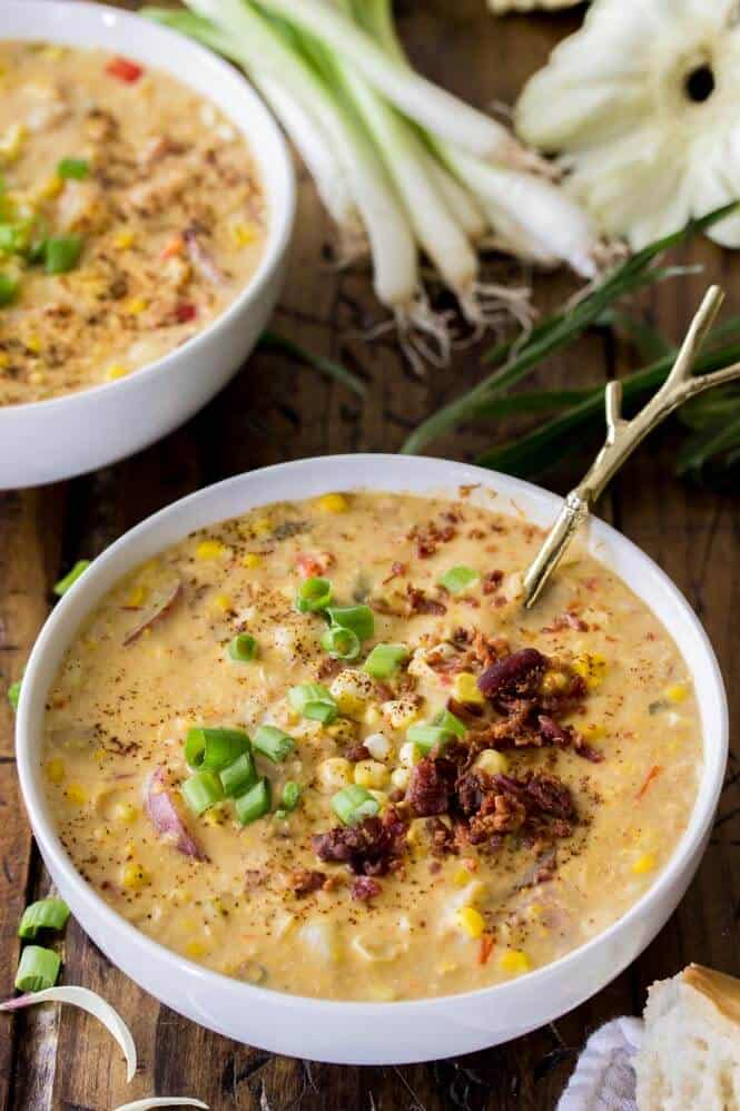 SUMMER CORN CHOWDER! A simple, hearty summer soup! #cornchowder #summerrecipe #sugarspunrun Corn chowder in white bowl, topped with bacon and chives