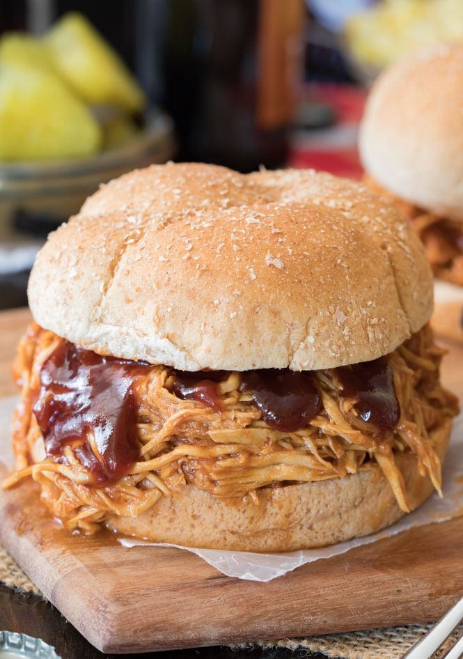How to make the BEST Pulled Chicken -- this is so easy and just requires a handful of ingredients! #bbqchicken #slowcooker #crockpotchicken #dinner #potluck #recipe A BBQ Chicken sandwich with extra bbq sauce over the meat
