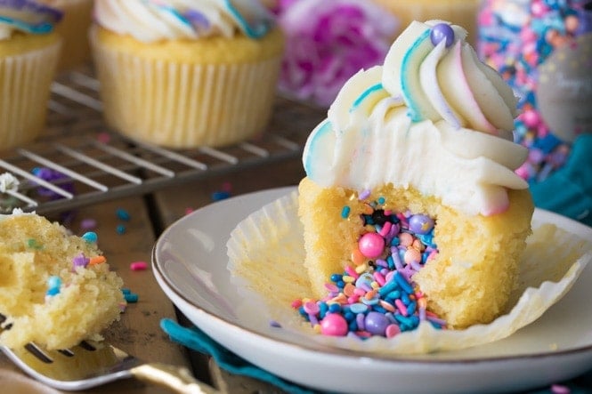 How to Make PINATA CUPCAKES! These are so fun and so easy to make! Pinata Cupcake with sprinkles spilling out of center onto plate