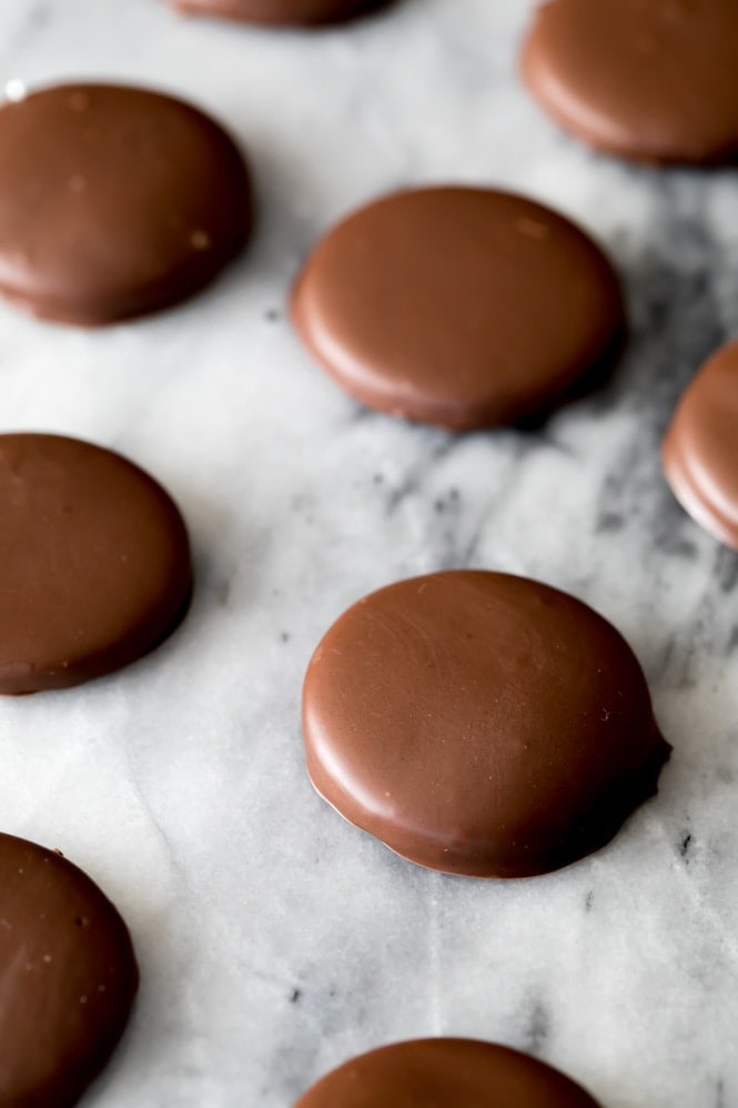 How to make Copycat Thin Mint cookies! Chocolate mint cookies arranged on an angle across a marble slab