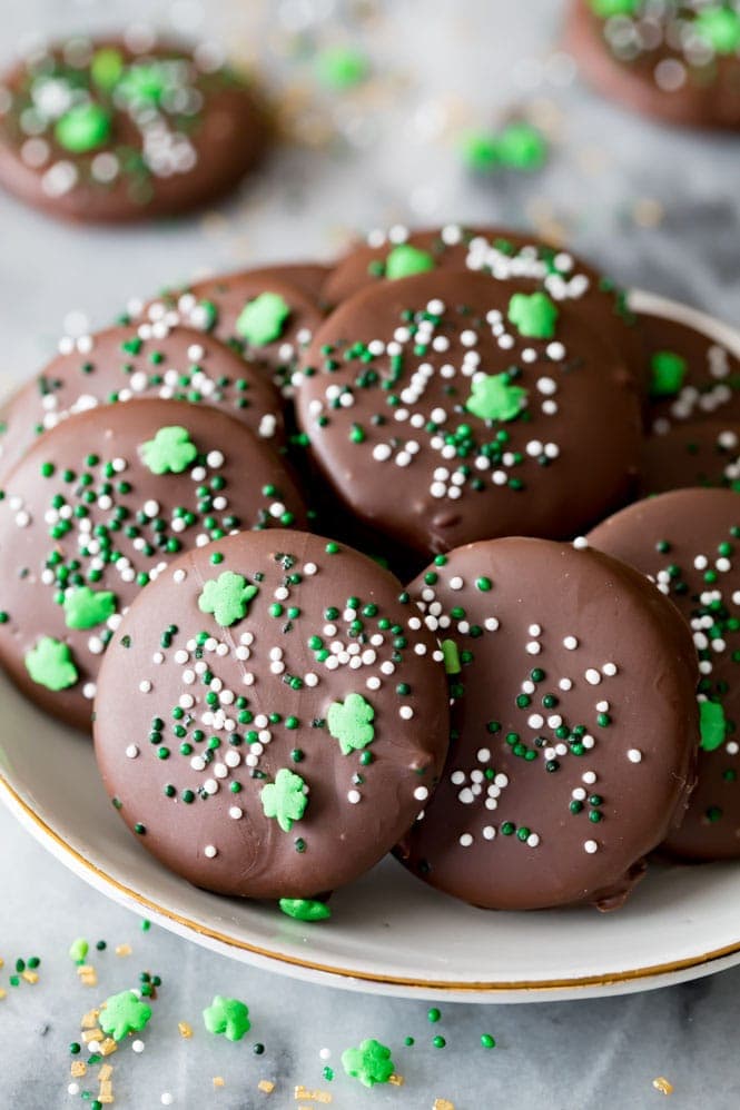 How to make Copycat Thin Mint Cookies at home! Decorate them with shamrocks in celebration of St. Patrick's Day! #cookie #thinmint #recipe #dessert #stpatricksday A plate full of copycat Thin Mint cookies decorated with festive St. Patrick's Day sprinkles