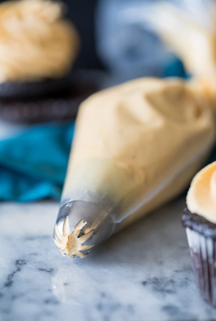 A silky smooth but perfectly pipeable peanut butter frosting that's the perfect complement to any cake or cupcake. Also great for just eating by the spoonful! #frosting #cupcake #recipe #baking #homemade peanut butter frosting in a piping bag