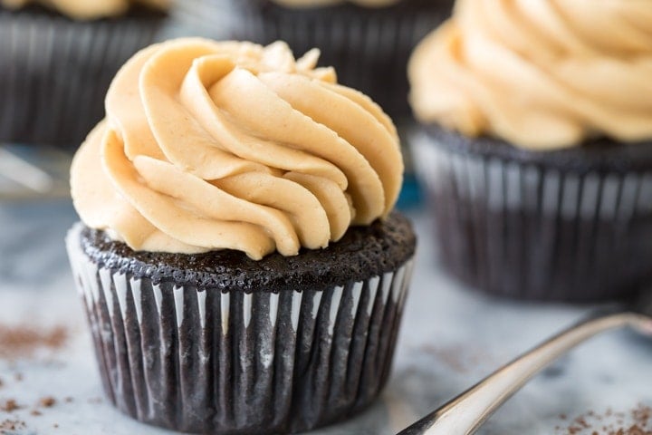 How to make a PEANUT BUTTER FROSTING that's silky smooth but perfectly pipeable, it's the perfect complement to any cake or cupcake. Also great for just eating by the spoonful! #frosting #cupcake #recipe #baking #homemade peanut butter frosting on a chocolate cupcake
