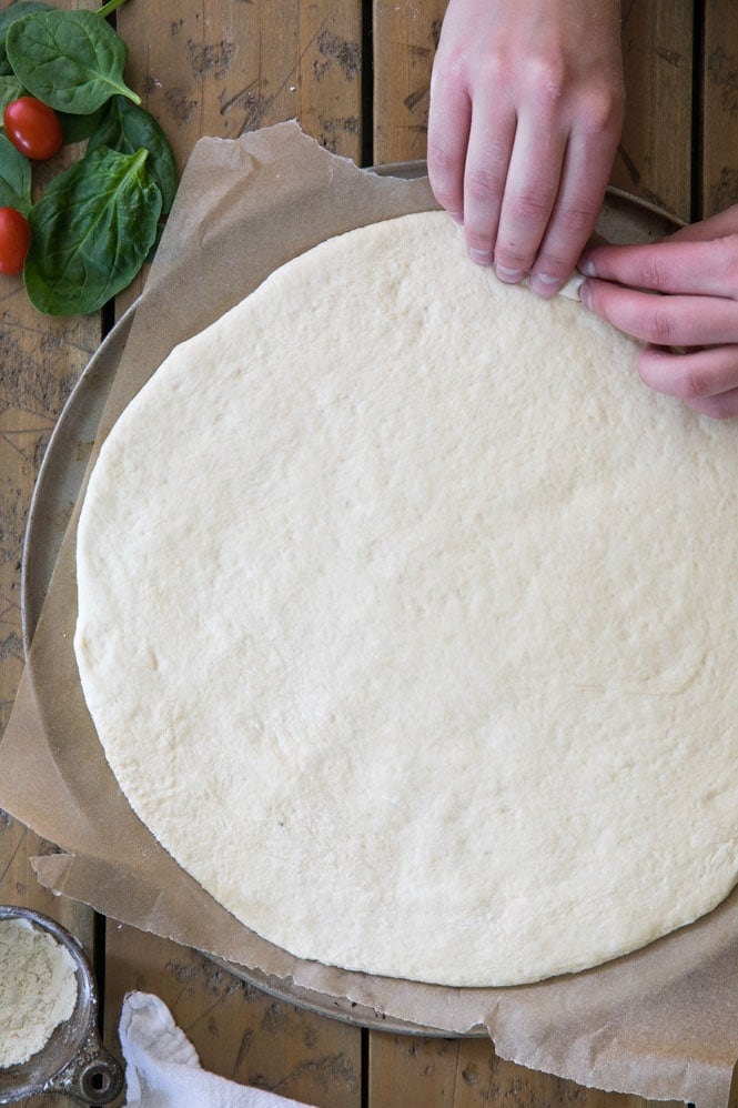 How to make the BEST pizza dough recipe. 10 minutes to prep and 30 minutes to rise for a this foolproof pizza dough! #pizzadough #pizza #baking #dinnerrecipe #easydinner Folding over pizza dough to form a crust