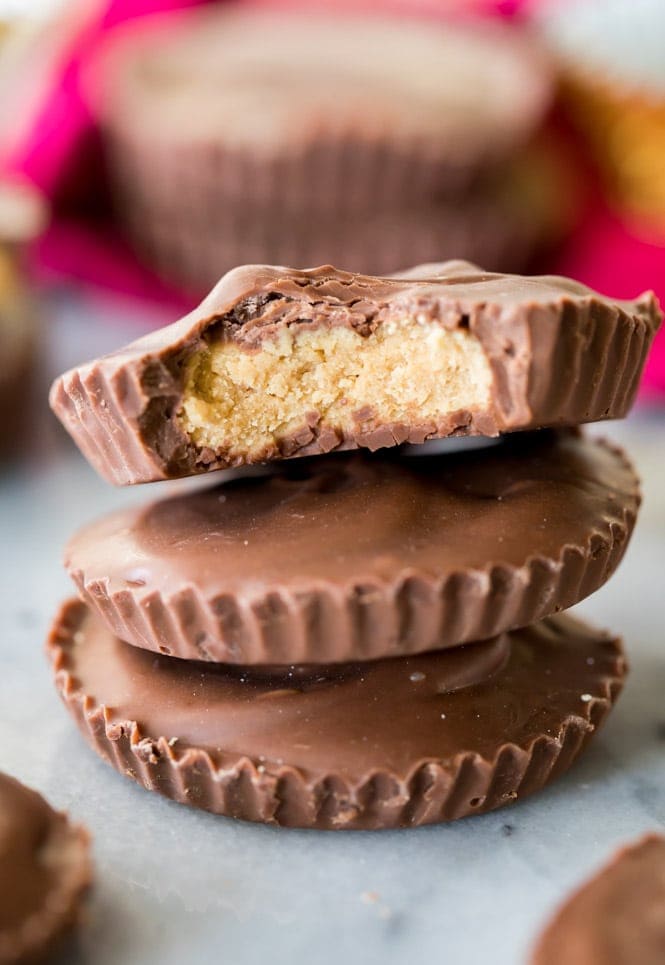 How to make homemade PEANUT BUTTER CUPS! These are so easy and so good! #peanutbutter #peanutbuttercups #candy #recipe #fromscratch #easyrecipe stack of three homemade peanut butter cups