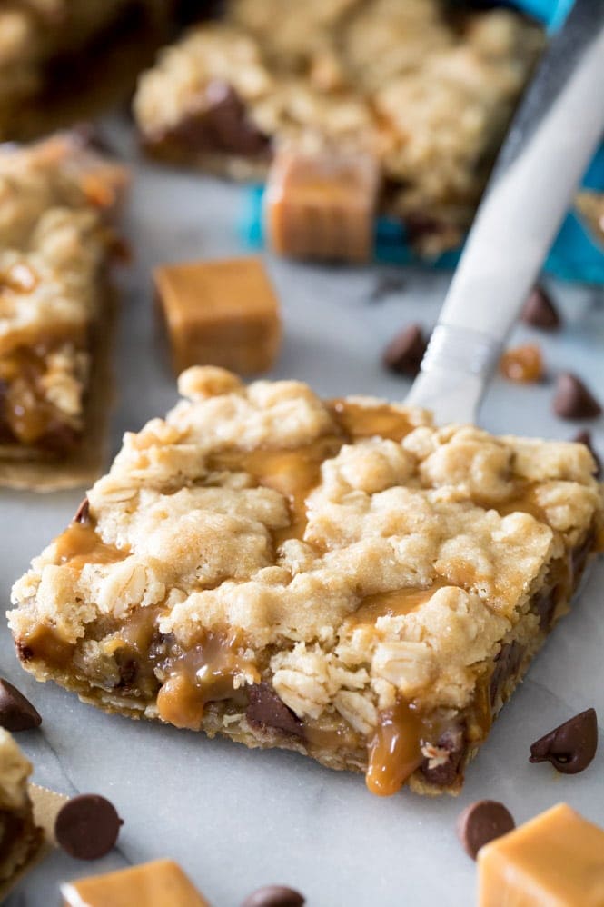 OMG these Carmelitas are amazing! Chewy, melty, caramel and chocolate filling encased in a buttery crisp cookie layer, these are a MUST try! #cookiebars #carmelitas #partyfood #bestdessert #easyrecipe Slice of caramelita on spatula