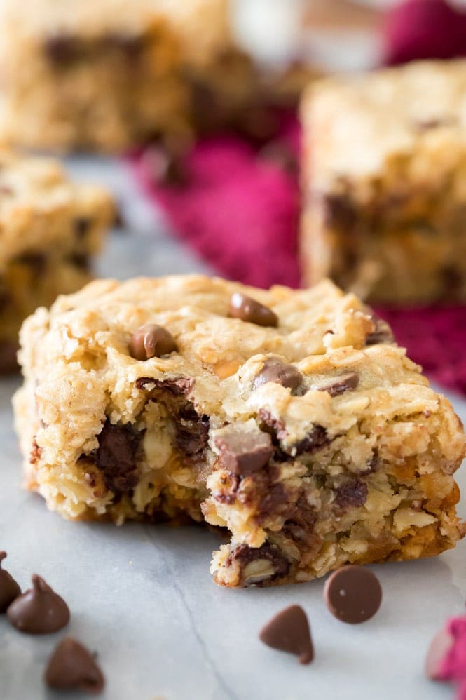 I love these OATMEAL COOKIE BARS! Hearty and packed with chocolate, these are so good! #cookiebar #easyrecipe #barcookie warm oatmeal cookie bar with melty chocolate