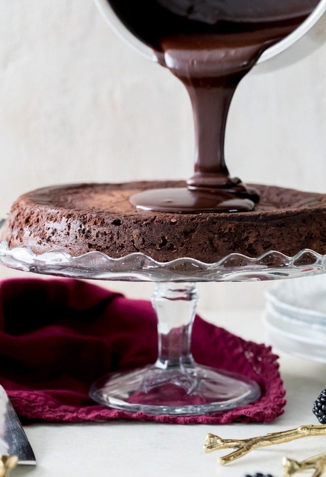 A rich, dense, & supremely fudgy FLOURLESS CHOCOLATE CAKE! #flourlesschocolatecake #glutenfree Pouring Ganache over cake