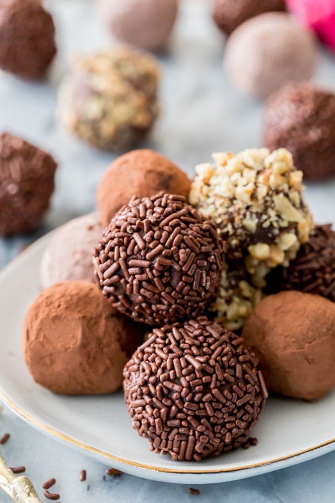 How to make homemade CHOCOLATE TRUFFLES! #homemadecandy #chocolate #chocolatetruffles an assortment of chocolate truffles on a white plate