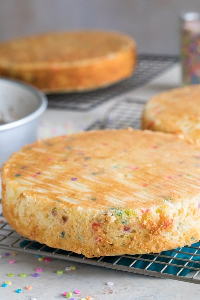 A simple recipe for a classic vanilla Birthday Cake. #birthdayparty #birthdaycake Three freshly baked layers of birthday cake cooling on wire rack
