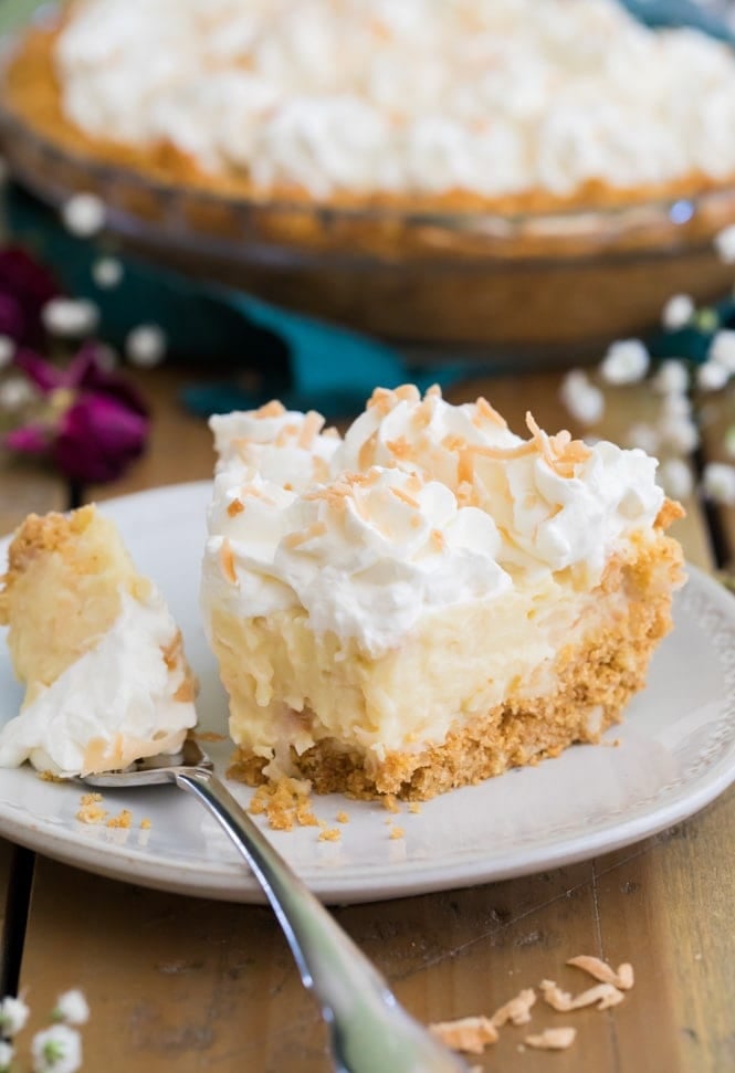 The BEST Coconut Cream Pie Recipe! #pierecipe #coconut #coconutcreampie Slice of coconut cream pie with bite out of it on white plate