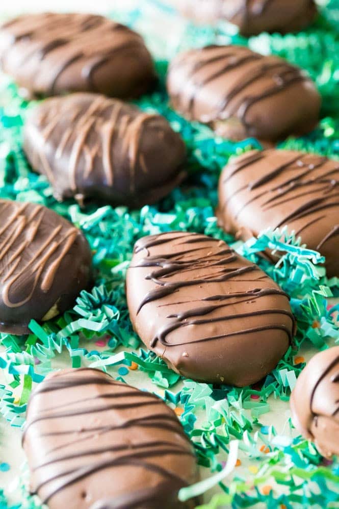 How to make homemade PEANUT BUTTER EGGS! The perfect Easter treat! #peanutbuttereggs #easterrecipe Chocolate covered Peanut Butter Eggs on green Easter grass