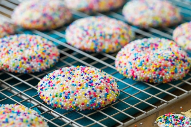 Fun, colorful, SPRINKLE COOKIES! Buttery chewy cookies encased in a colorful sprinkle shell! #cookierecipe #bestcookies Sprinkle cookies on cooling rack