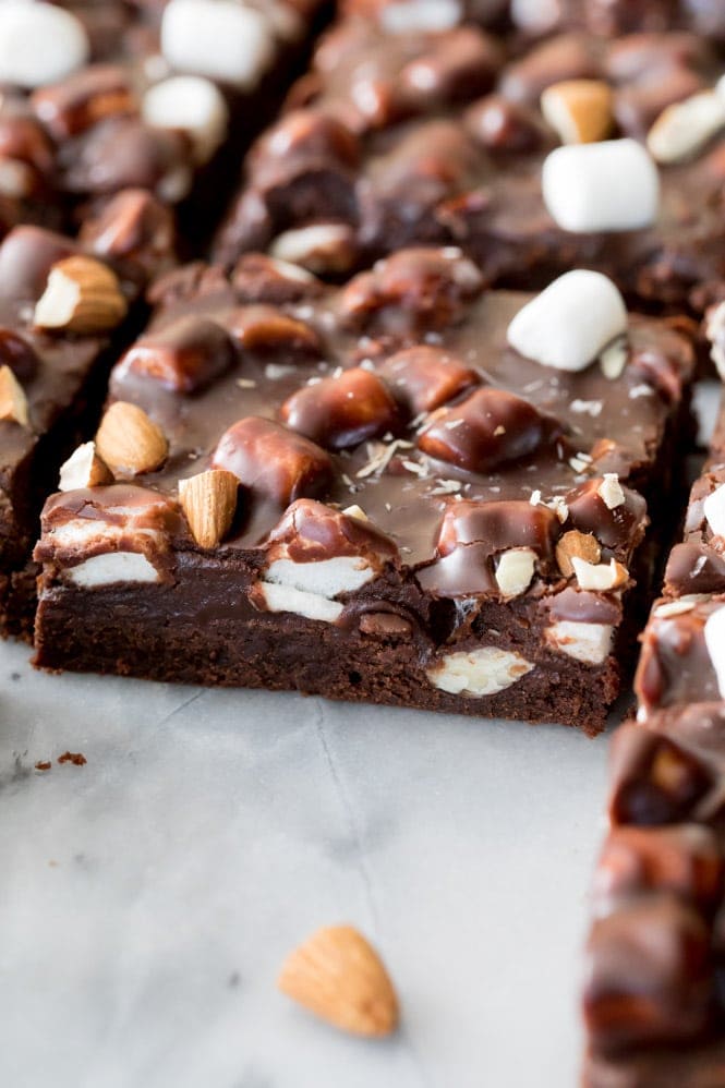ROCKY ROAD BROWNIES! Fudgy, chewy, homemade brownies topped off with a chocolate, marshmallow, and almond coating! These are INCREDIBLE! #brownies #rockyroad Sliced Rocky Road Brownies on marble