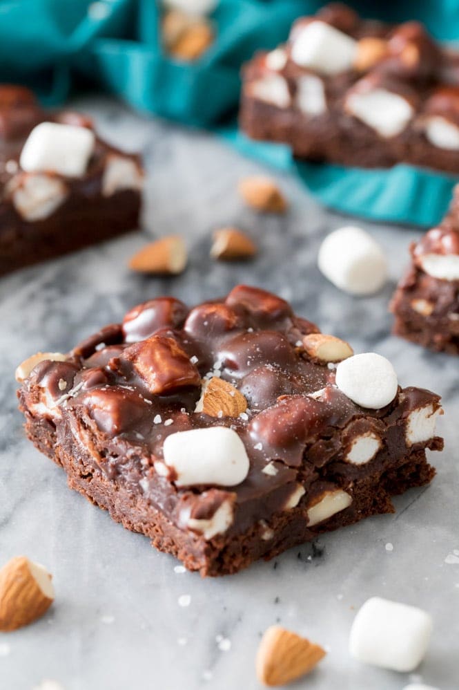 ROCKY ROAD BROWNIES! Fudgy, chewy, homemade brownies topped off with a chocolate, marshmallow, and almond coating! These are INCREDIBLE! #brownies #rockyroad Slice of Rocky Road Brownies on marble