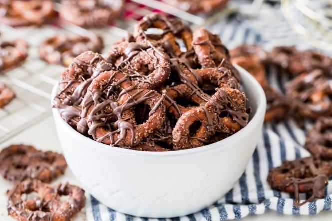 Snappy, chocolate-y, tossed in cinnamon, sugar, and butter, these CANDIED PRETZELS make a great and easy party snack! #partyfood #easyrecipe #sugarspunrun White bowl of candied pretzels