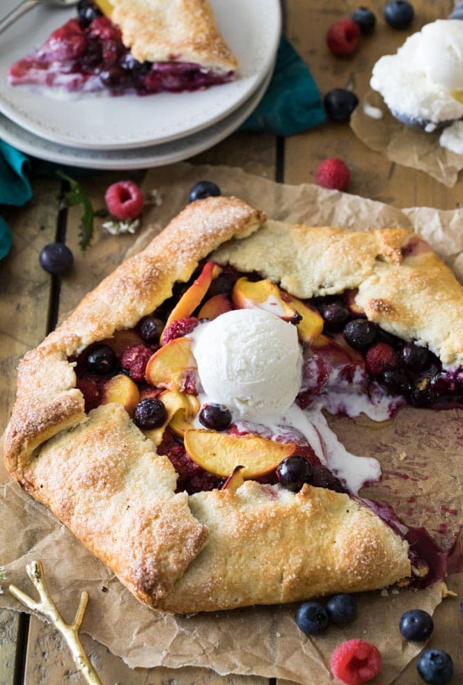How to make a simple fruit galette recipe! Galettes are easier to make than fruit pies, but every bit as tasty. #summerrecipe #easypierecipe #sugarspunrun #easyaspie Slicing into a fruit galette that's topped with vanilla ice cream