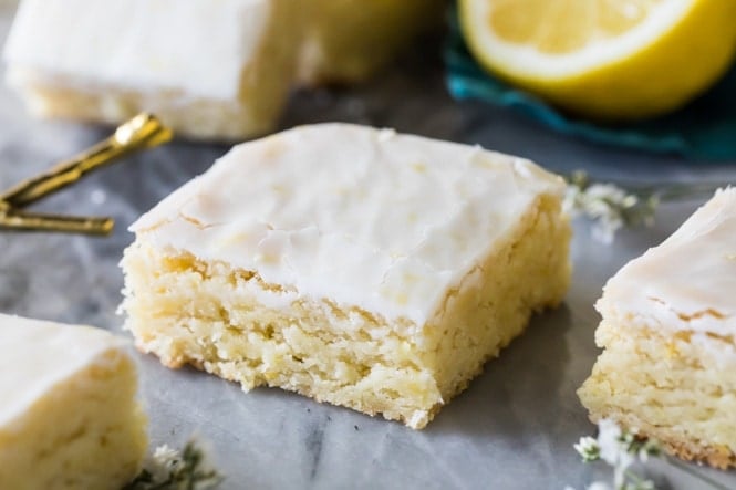 These LEMON BROWNIES are so soft and refreshing, absolutely bursting with lemon flavor! Great lemon dessert, a perfect summertime treat! #summerdessert #lemondessert #lemonbrownies #sugarspunrun Lemon brownie square on white marble