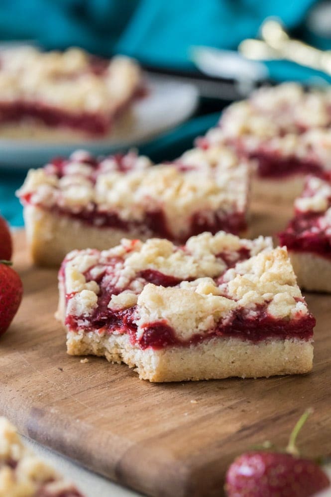 Strawberry Crumb Bars! Refreshing buttery bars with a bright homemade strawberry jam filling. #sugarspunrun #strawberrybars #strawberrydessert #strawberrydessert Strawberry crumb bar with a bite out of it