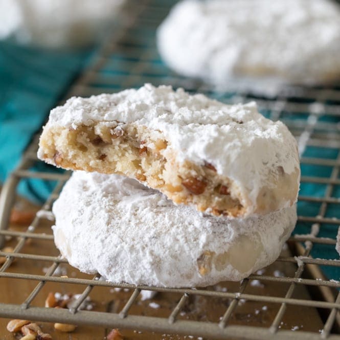 Pecan sandies stacked on top of each other on wire cooling rack with bite taken out.