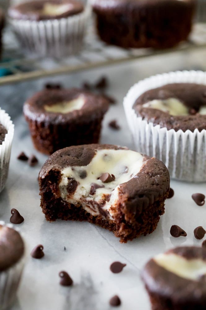 How to make classic BLACK BOTTOM CUPCAKES! Fudgy chocolate bottoms and rich cheesecake centers! So easy and so good! #chocolatecupcakes #blackbottomcupcakes #sugarspunrun Black bottom cupcake with a bite out of it, showing cheesecake center