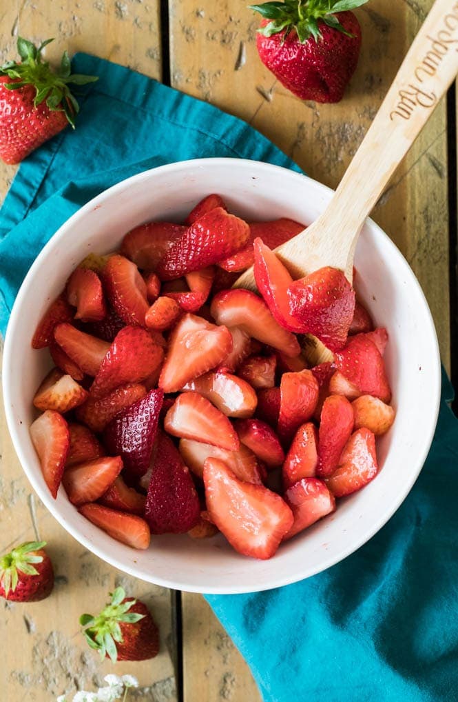 How to make a sweet and simple STRAWBERRY COBBLER! Easy and made completely from scratch, this recipe is a great way to use up summertime berries! #strawberryrecipe #cobblerrecipe #sugarspunrun #summerbaking White bowl full of strawberries to make strawberry cobbler