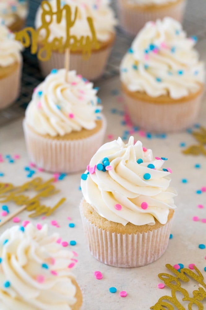 A sweet and simple recipe for Gender Reveal Cupcakes! Fill them with either pink or blue sprinkles for a fun surprise reveal #genderreveal #genderrevealcupcakes #genderrevealcake #babyshower #sugarspunrun Gender reveal cupcakes: yellow cupcakes with swiss meringue buttercream frosting and blue and pink sprinkles
