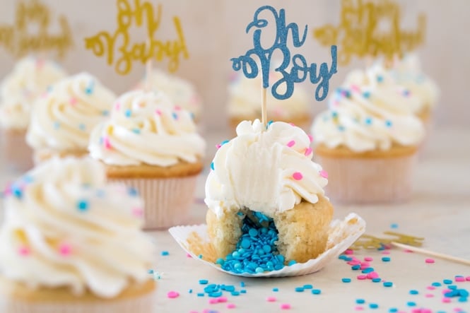 A sweet and simple recipe for Gender Reveal Cupcakes! Fill them with either pink or blue sprinkles for a fun surprise reveal #genderreveal #genderrevealcupcakes #genderrevealcake #babyshower #sugarspunrun Vanilla cupcake with blue sprinkles in center