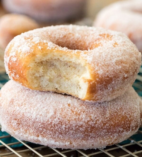 Sugared donuts stacked on top of each other. Top one has bite taken out