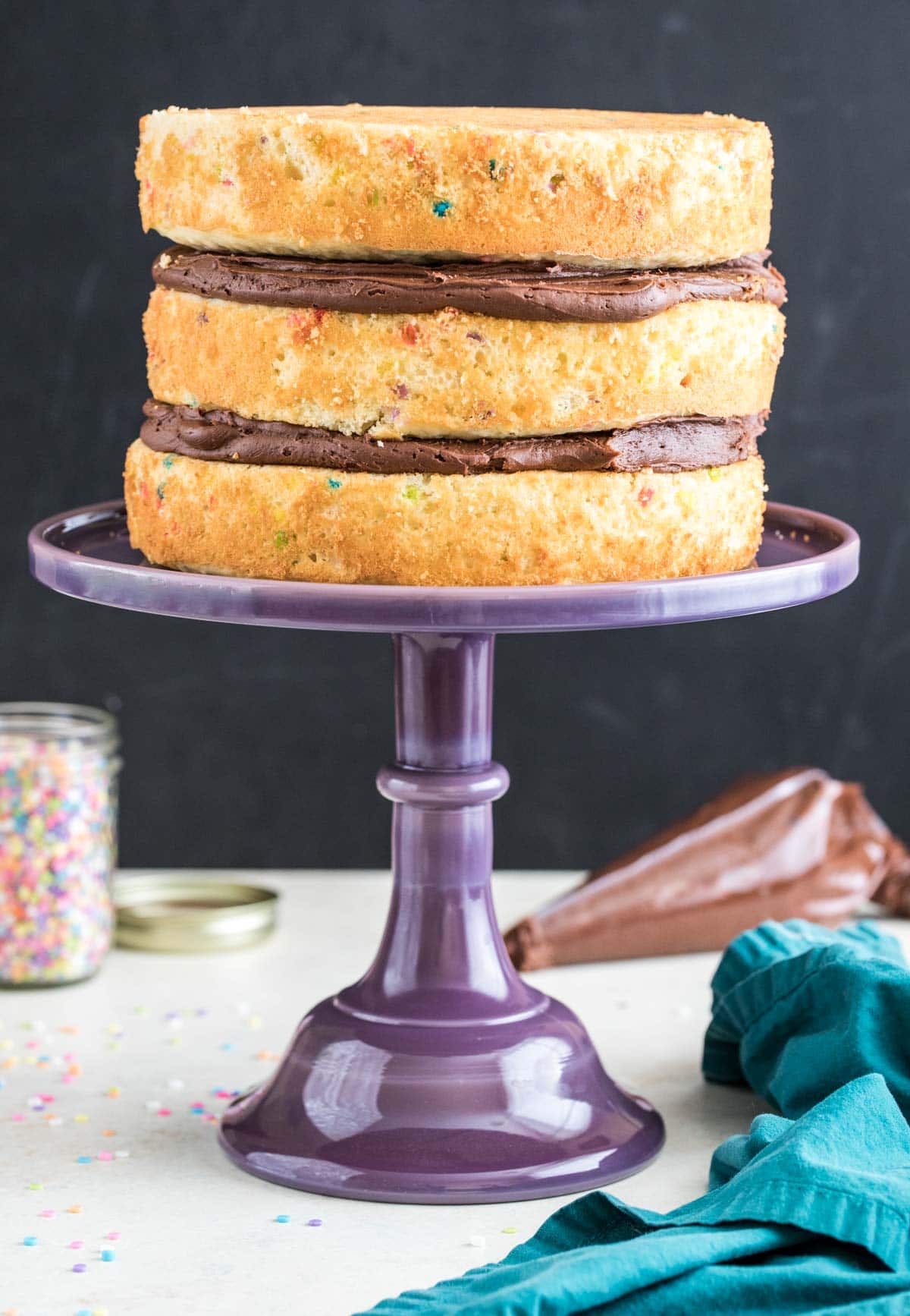 Purple glss cake stand with three layer cake on top
