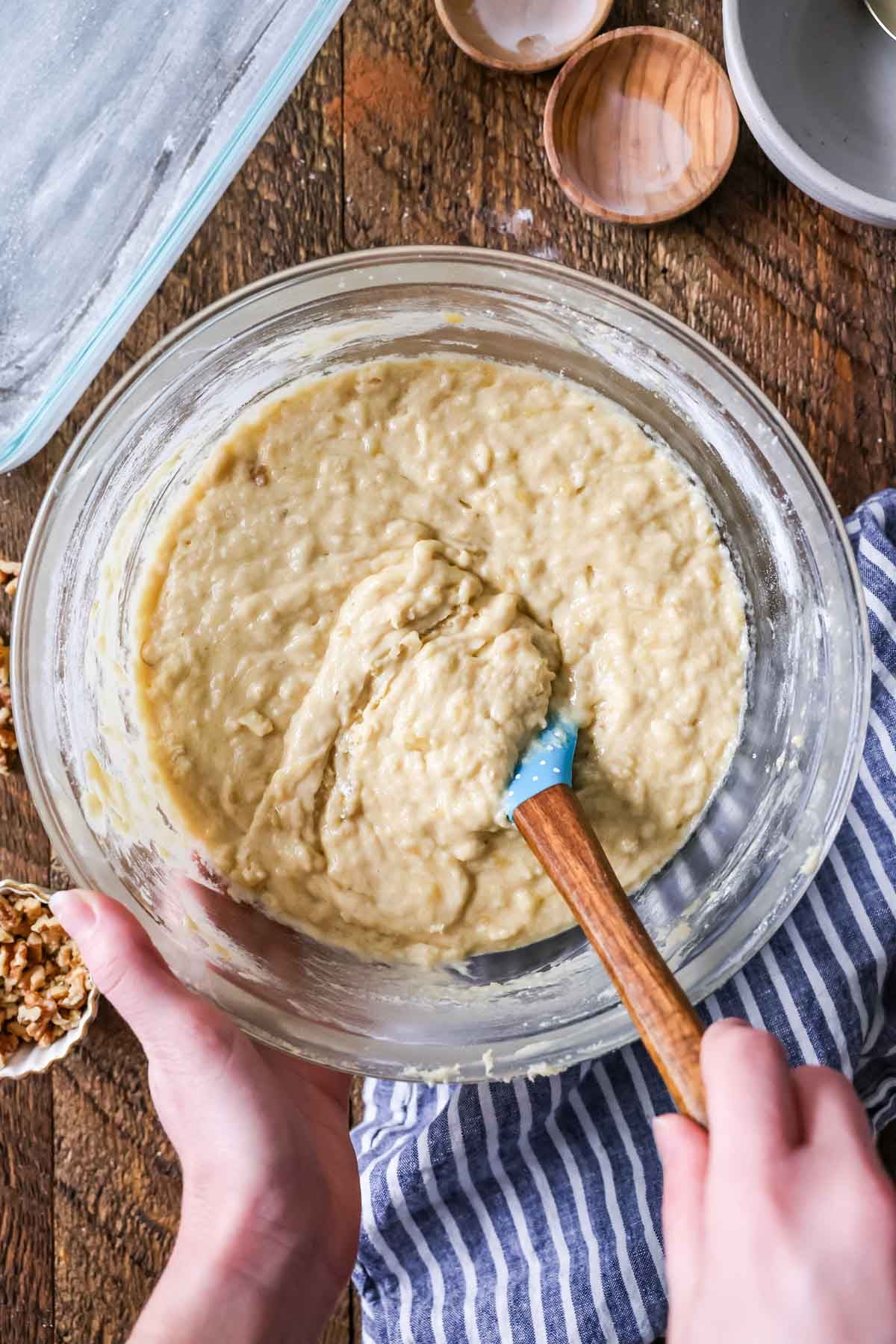 Overhead view of banana cake batter in a glass mixing bowl.