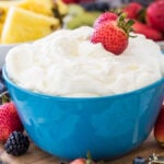 Fruit dip in a blue bowl with strawberries in it.