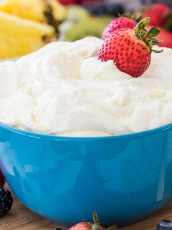 Fruit dip in a blue bowl with strawberries in it.