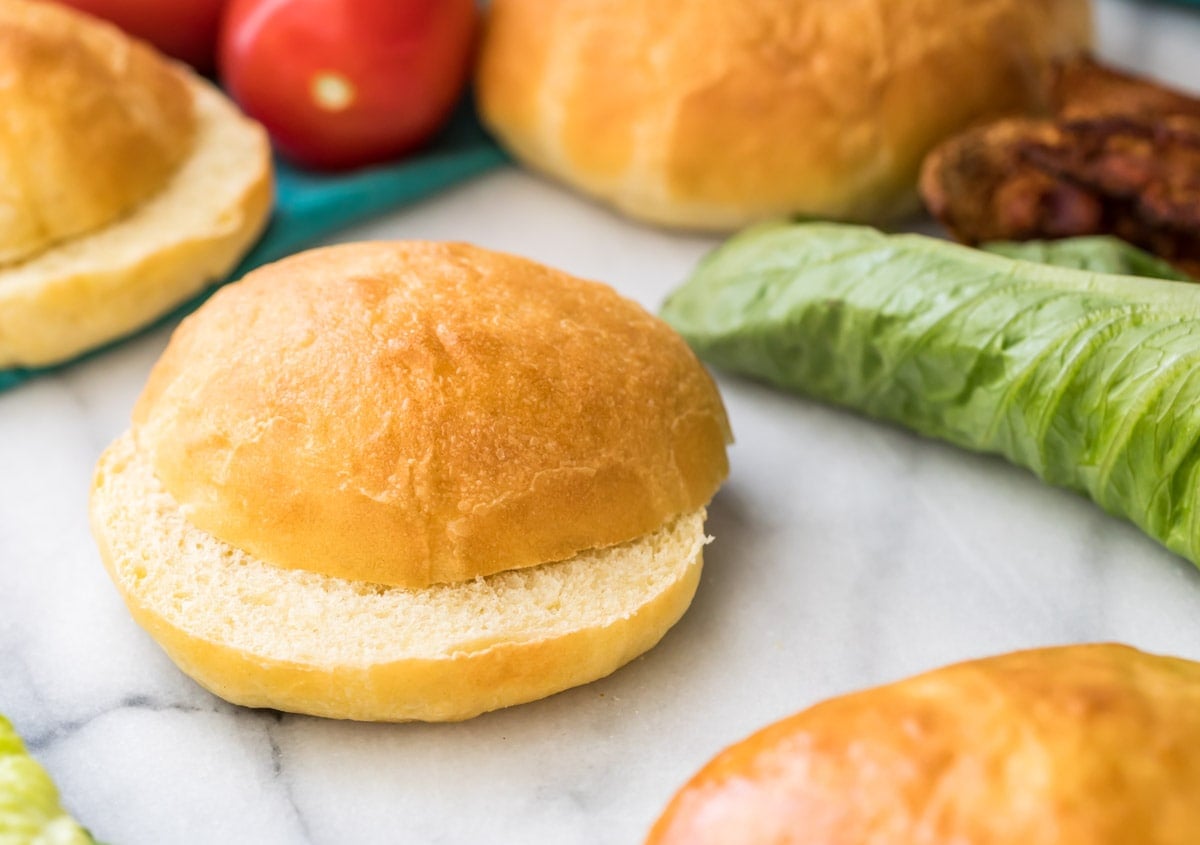 sliced potato bun on marble with lettuce and more buns in background