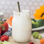 mason jar full of ranch dressing centered in photo with honeycomb tile background and fresh veggies surrounding jar