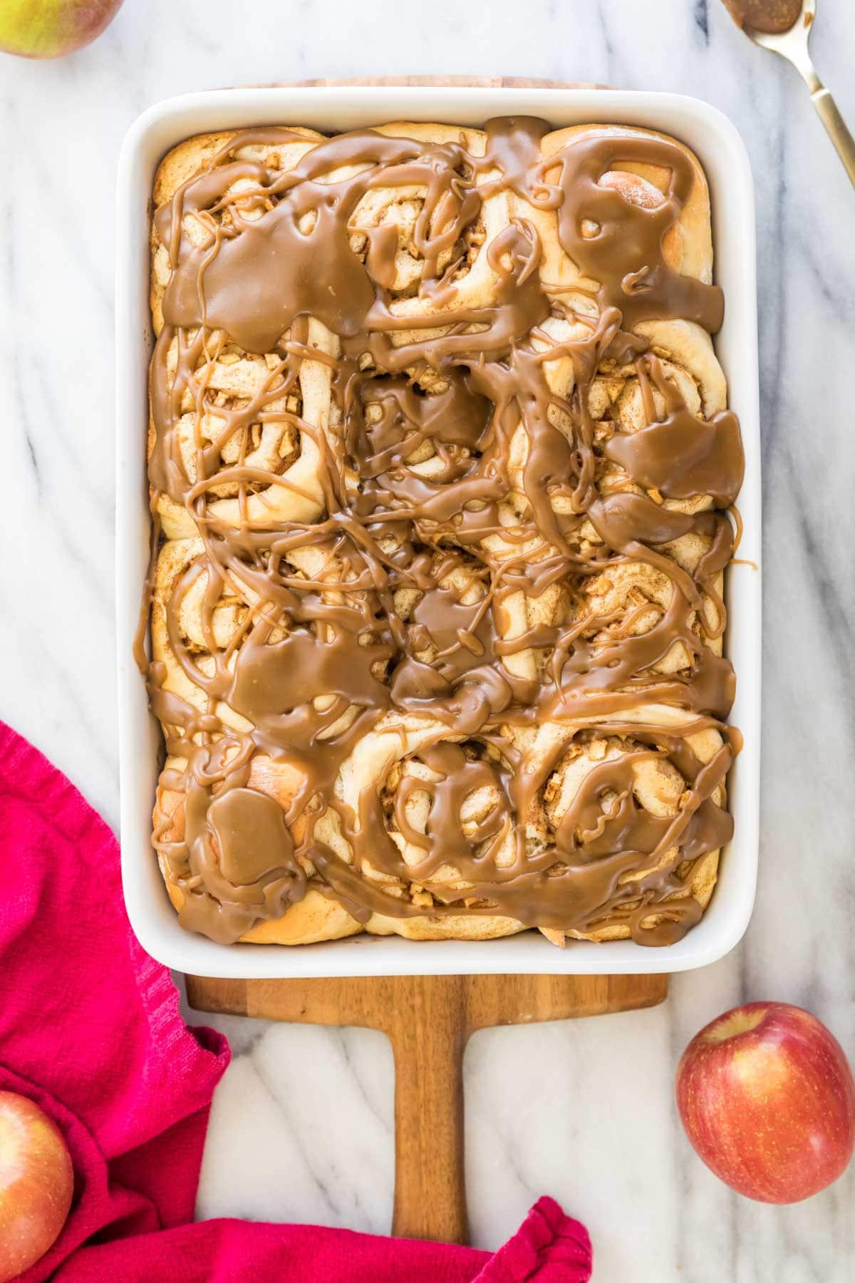 overhead view of rectangular baking dish full of apple cinnamon rolls sitting on white countertop