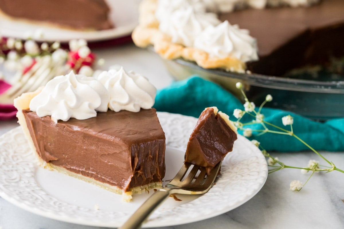 Slice of homemade chocolate pie and fork with bite sitting on white plate