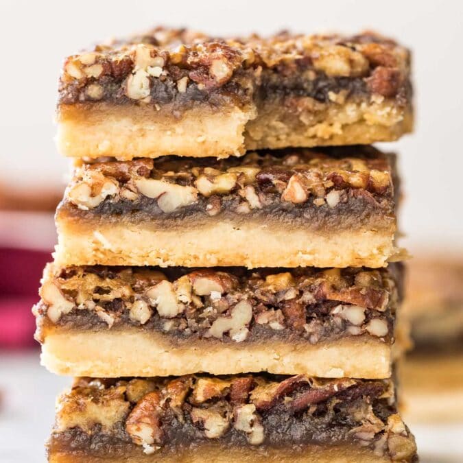 four pecan pies stacked on top of each other, with the top bar missing one bite