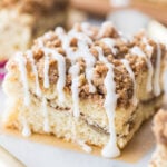 square slice of cinnamon coffee cake with a cinnamon swirl middle, crumb topping, and vanilla drizzle glaze