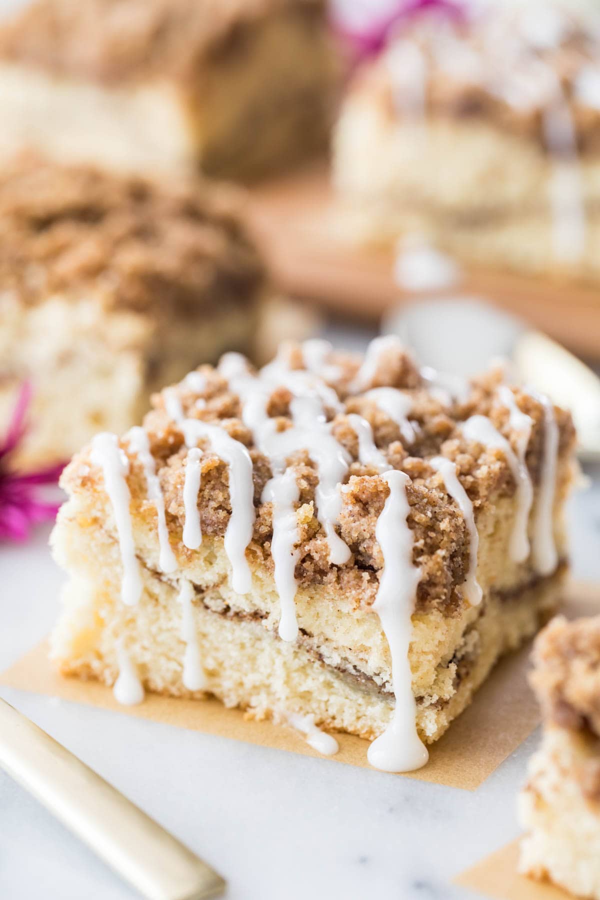 square slice of cinnamon coffee cake with a cinnamon swirl middle, crumb topping, and vanilla drizzle glaze