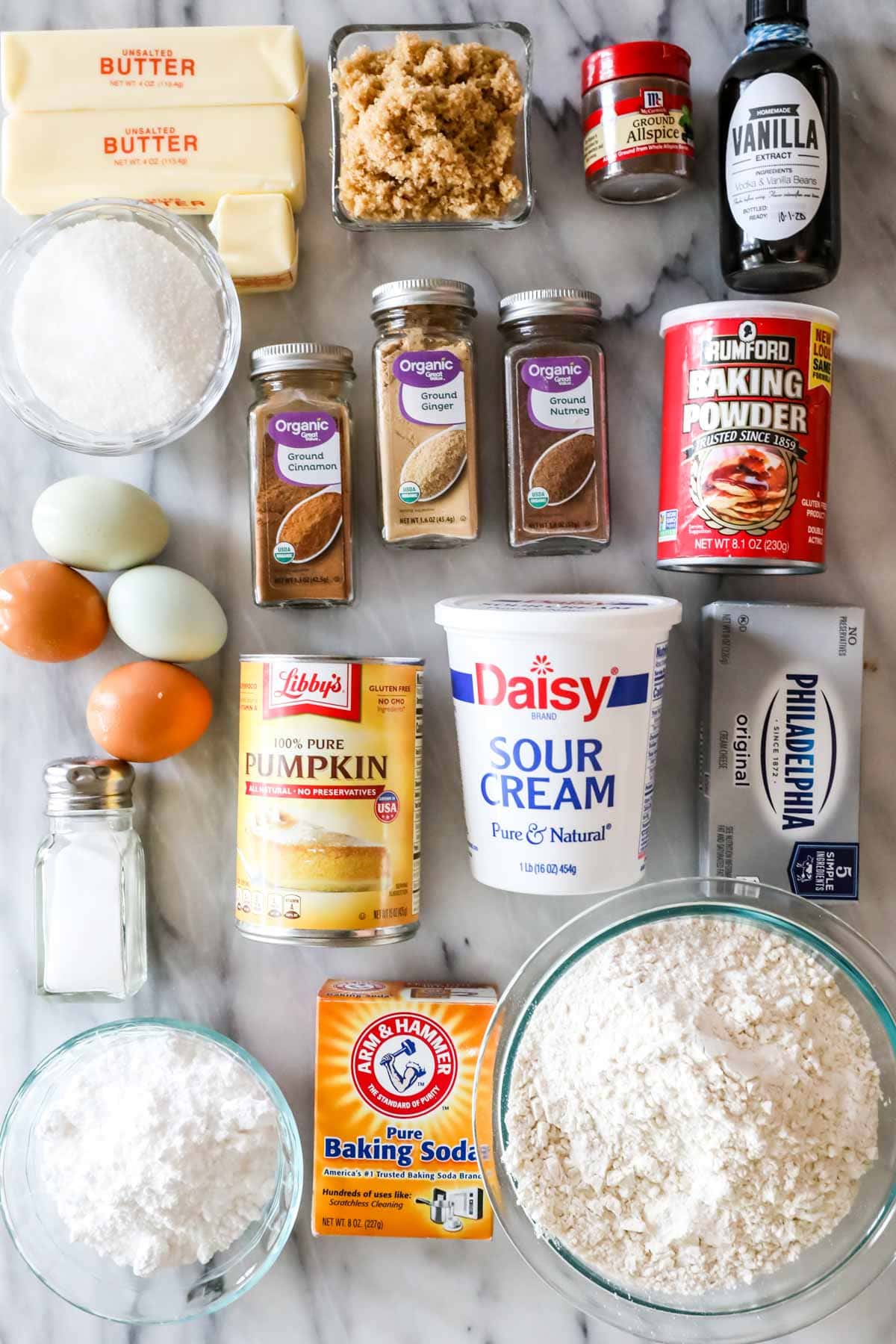 Overhead view of ingredients including butter, pumpkin, eggs, spices, and more.