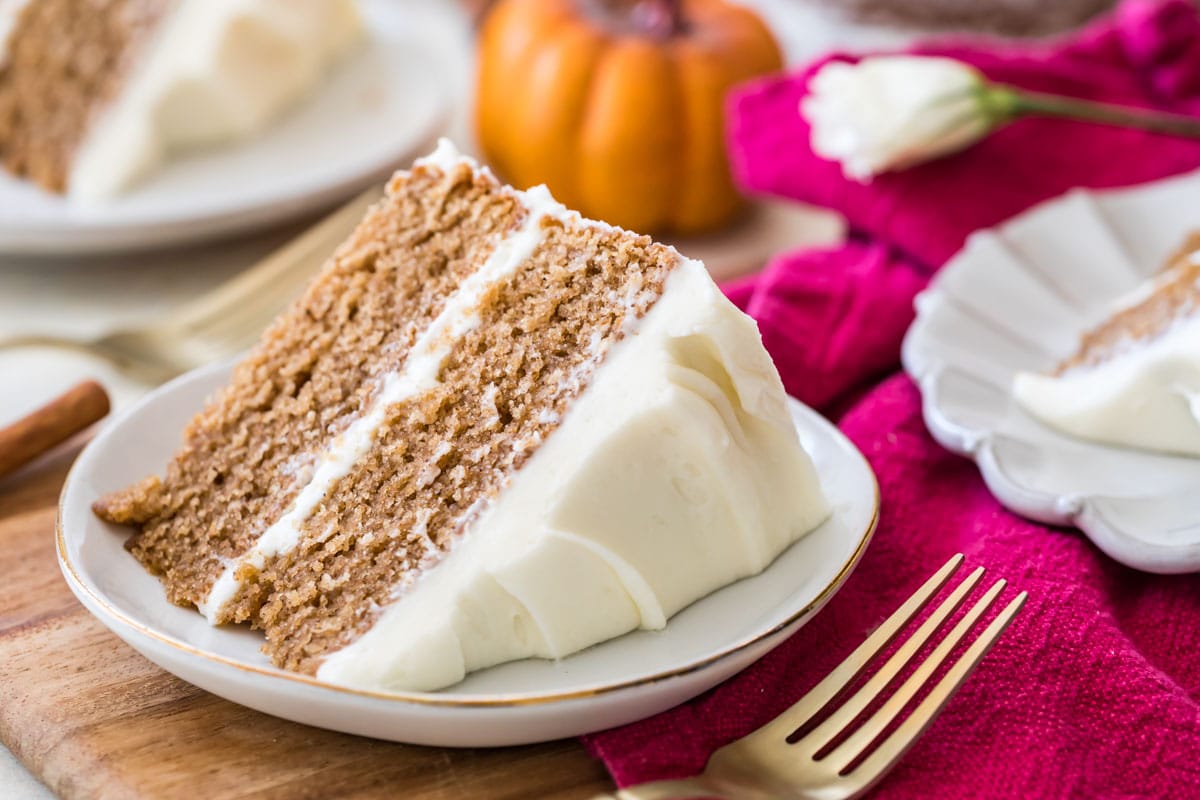 Cream cheese frosted cake slice on a white plate.