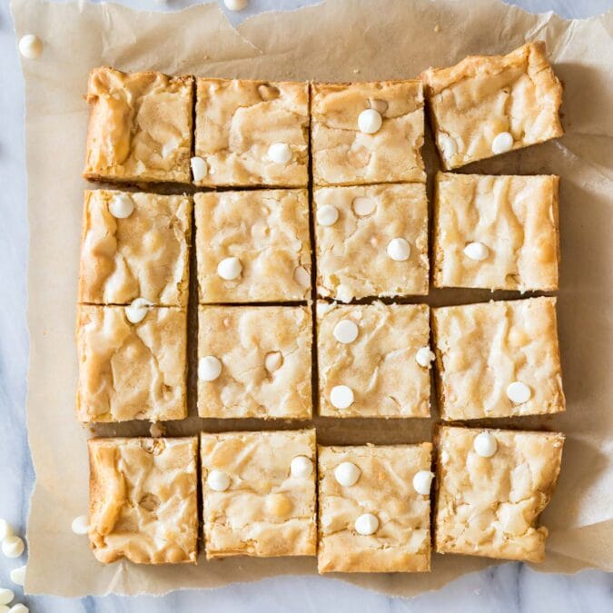 Overhead view of a batch of white chocolate brownies cut into 16 pieces.