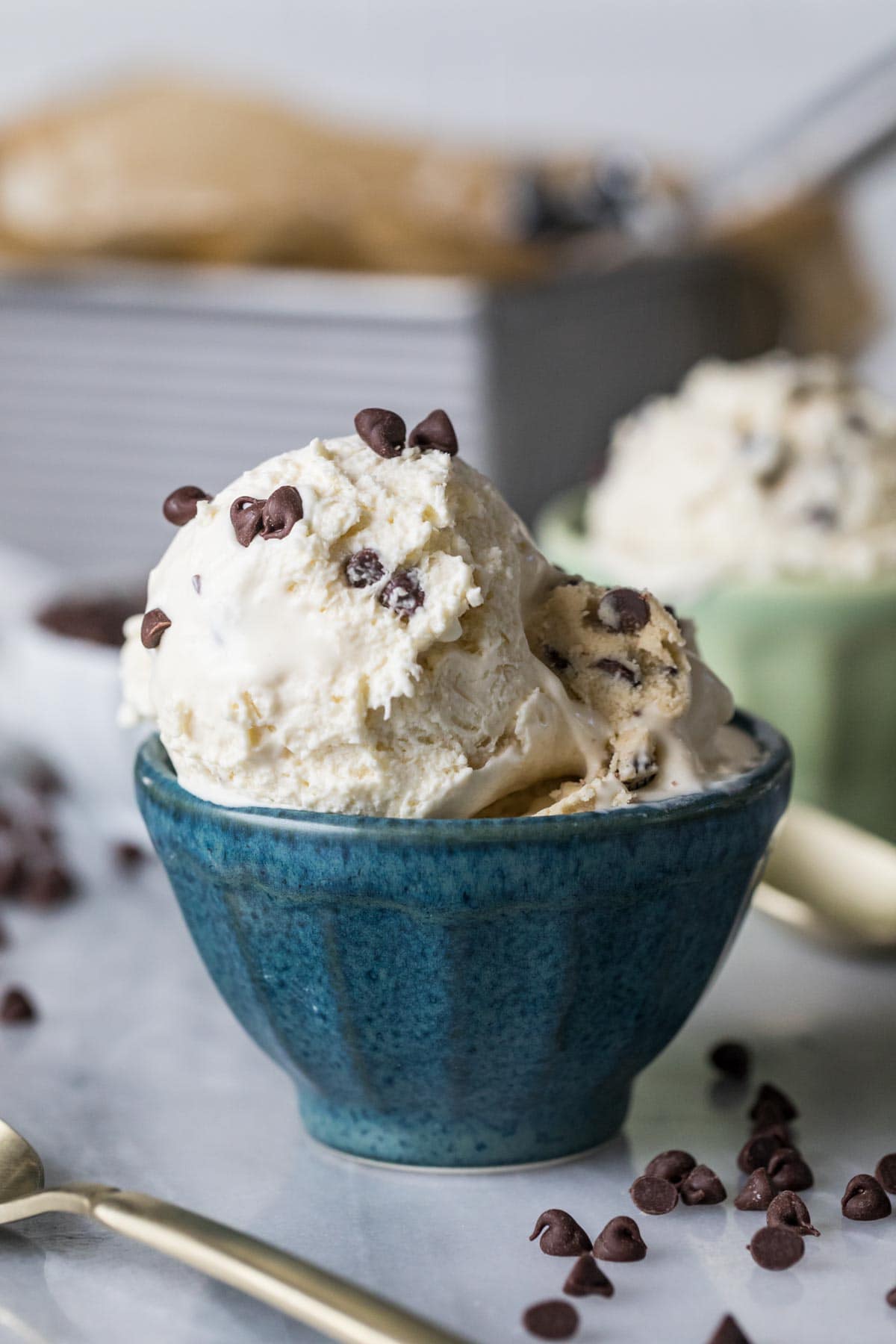 Close-up view of a small blue bowl of homemade ice cream topped with chocolate chips.