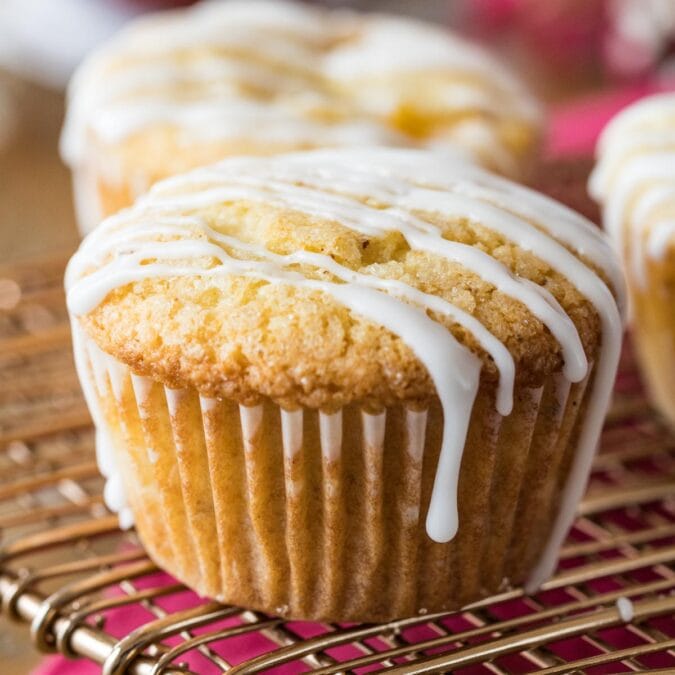 Peach muffins drizzled with vanilla glaze on a cooling rack.