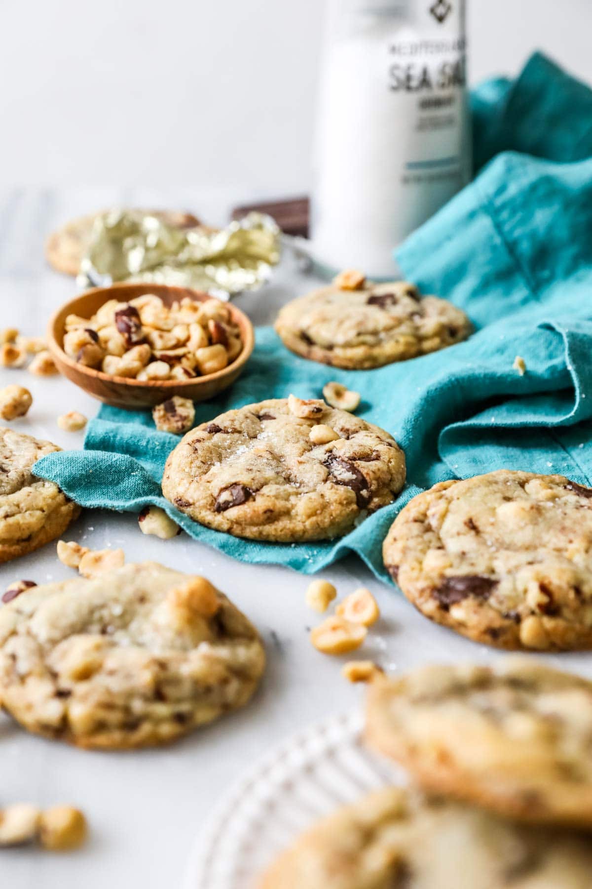 Teal tea towel with chocolate chip cookies scattered across it.