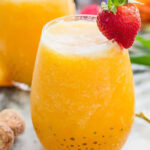 Frozen peach bellini in a glass with a strawberry garnish.